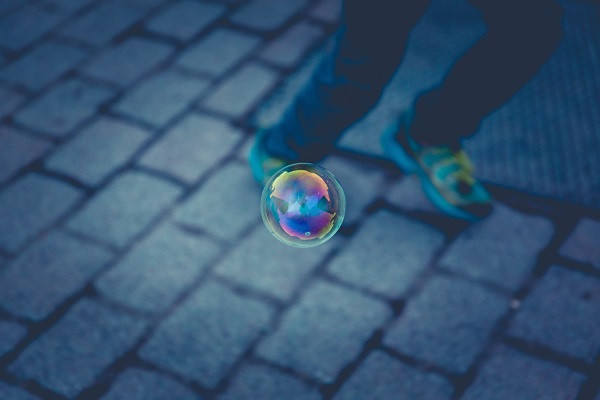 Man walking on urban street with soap bubble floating by