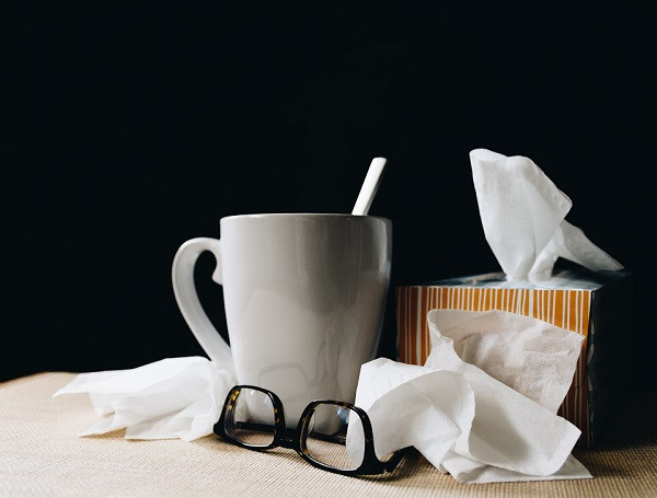 A hot drink, box of tissues, used tissues and glasses