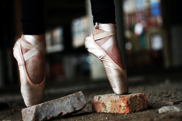 Ballet dancer balanced en pointe on broken concrete