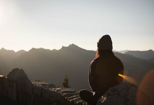 Women sitting at sunrise with mountains in distance