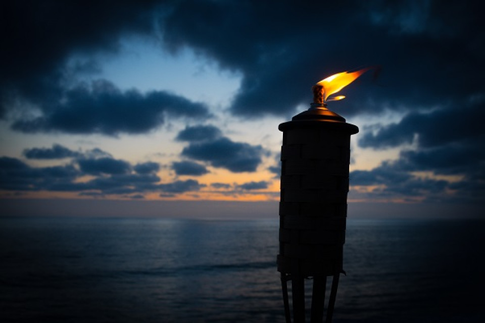 Fire torch against the sea and sky at nightfall