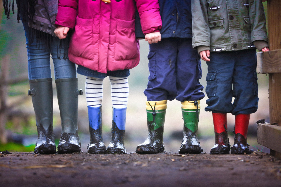 Mud covered gumboots and legs of three children and an adult