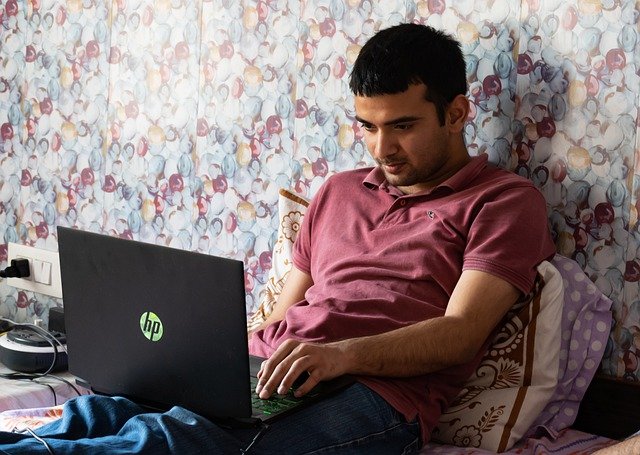 Man working on a laptop on his bed