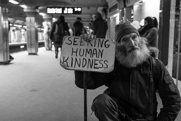 Man holding a sign saying seeking human kindness