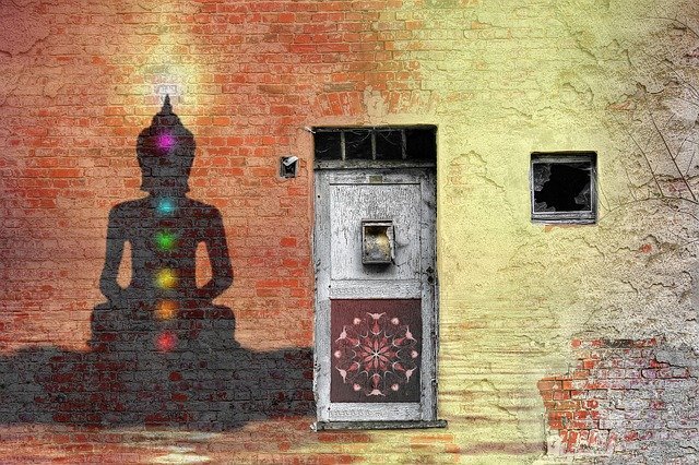 Buddha outline on brick wall with coloured chakra centres