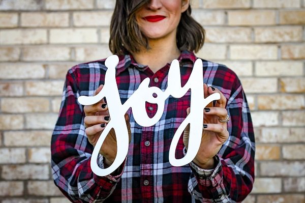 Woman holding the word joy painted between her hands