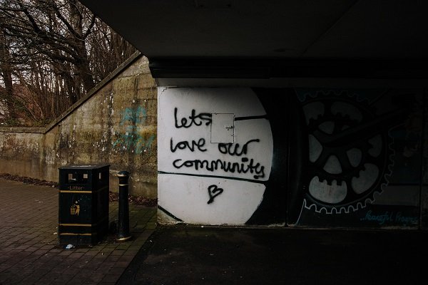 Concrete underpass with graffiti saying let's love our community