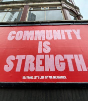 Red billboard saying community is strength
