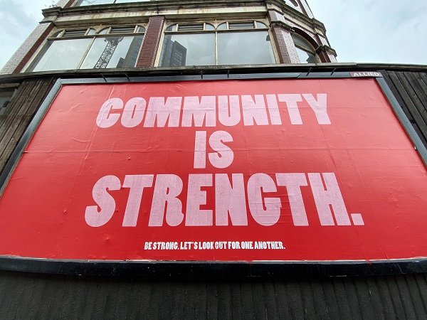 Red billboard saying community is strength